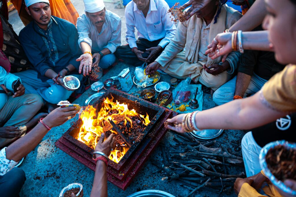 Group of Indian people performing a traditional Hindu ritual around a sacred fire.
